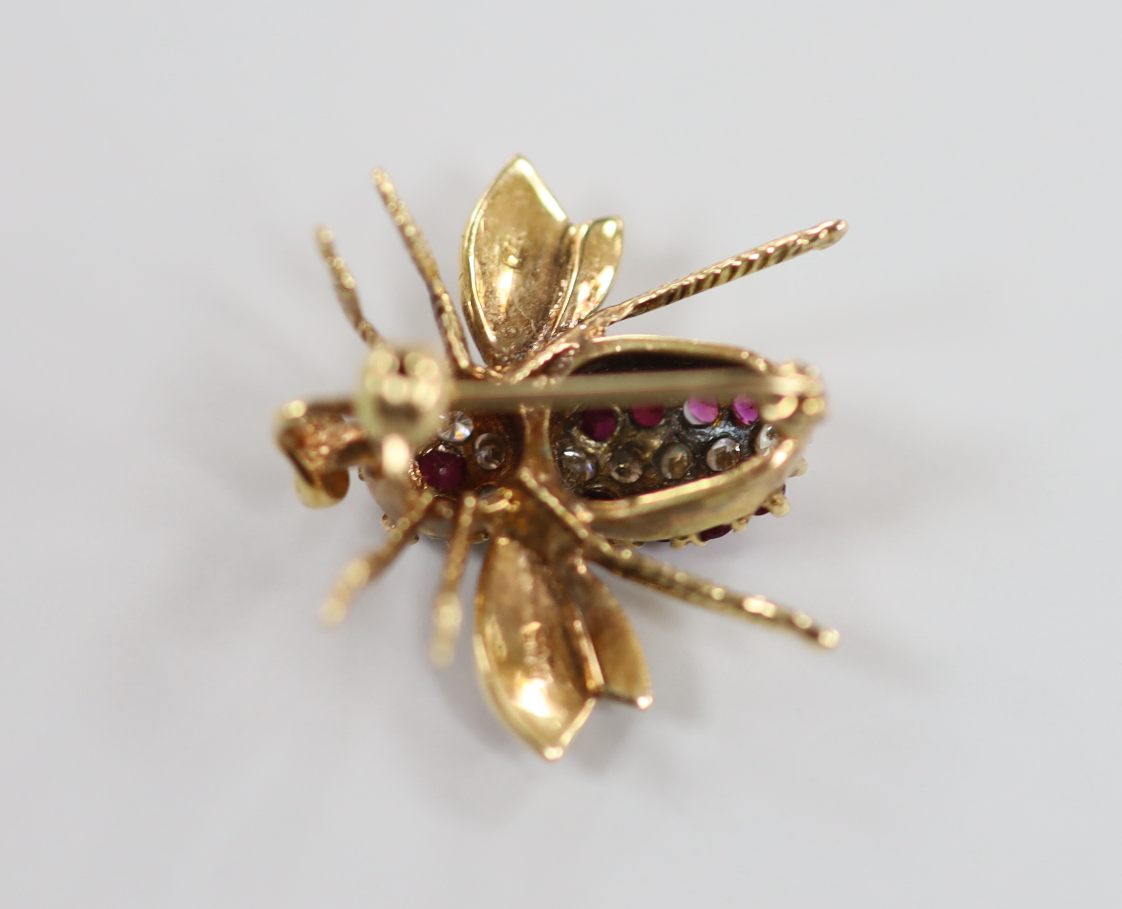 A 14k yellow metal, ruby and diamond cluster set bug brooch, 20mm, gross weight 3.1 grams.